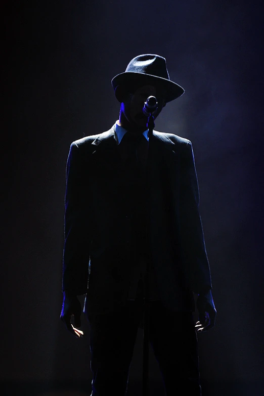 a person in a dark suit with a hat on the phone