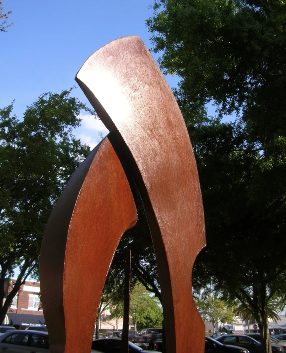 a sculpture of a large curved metal piece on a concrete slab