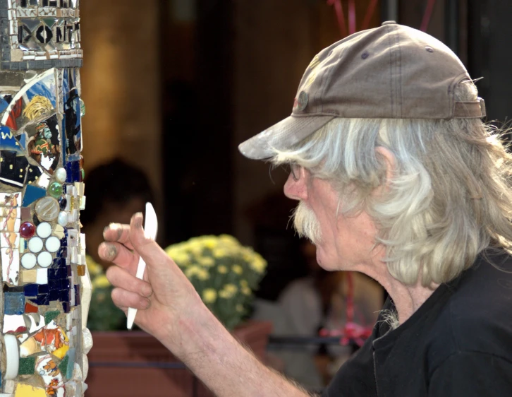 an elderly man smoking a cigarette next to a stained glass display