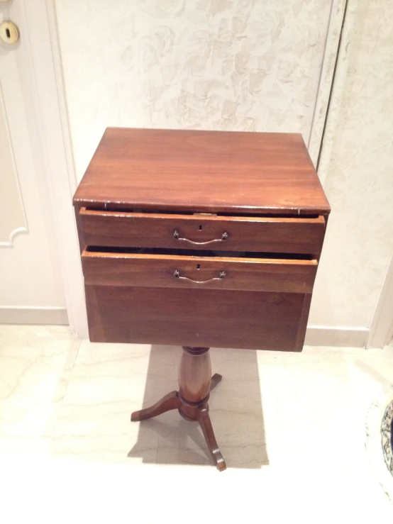 a dark wooden desk with a small drawer on the top