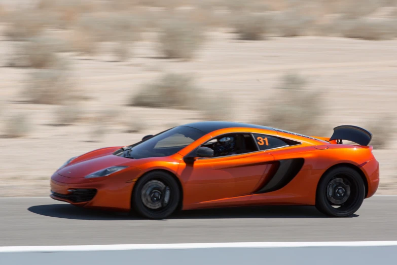 the orange sports car drives on a track