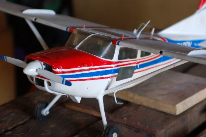 small red and blue model plane sitting on top of a wooden table