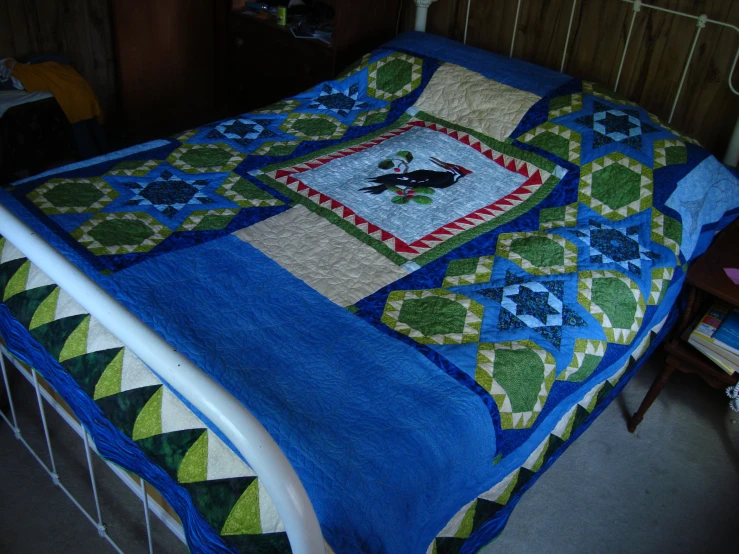 a small bed with a quilt and blanket on it