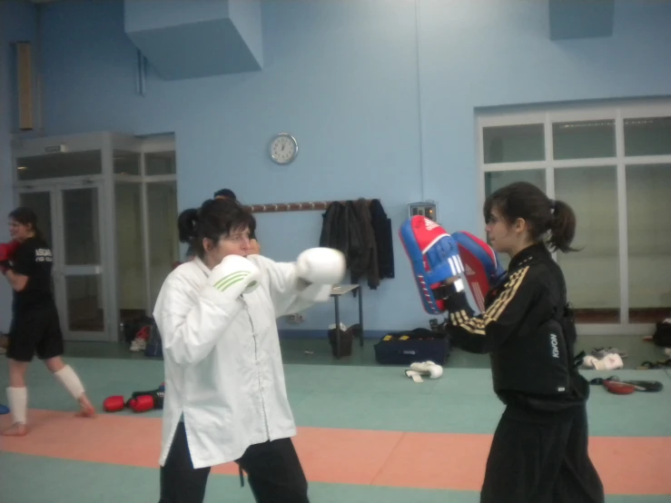 two people in uniform practicing boxing, one with a ball and a glove