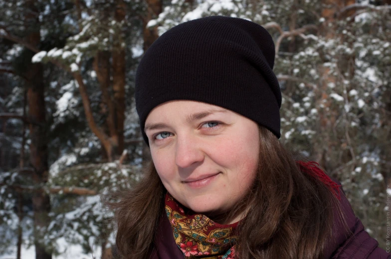 a girl smiling in the snow, wearing a black hat and coat