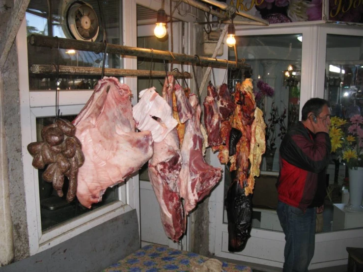 a person that is looking at some meat hanging