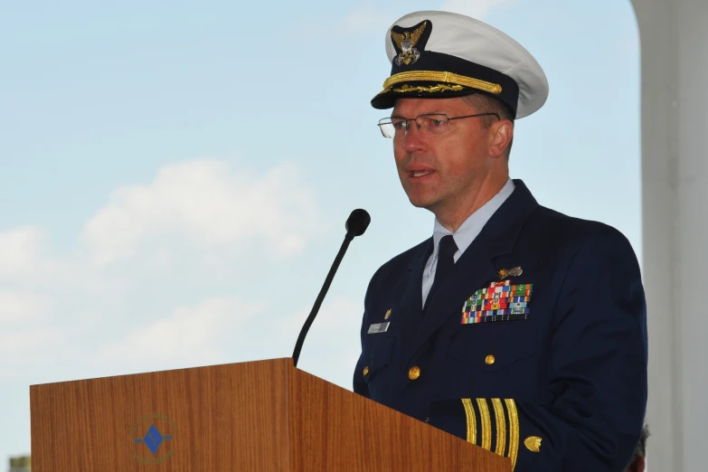 a naval official in uniform standing at the podium