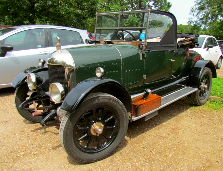 a green old car parked next to other cars