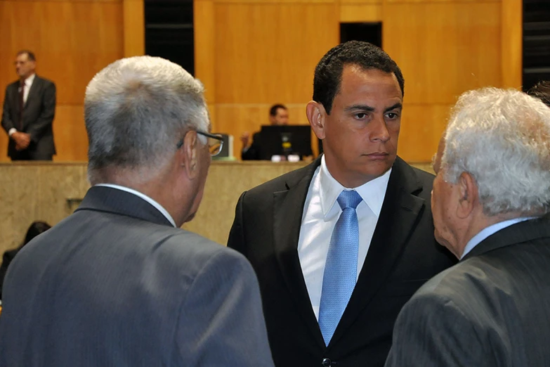 three men in suits are standing and talking