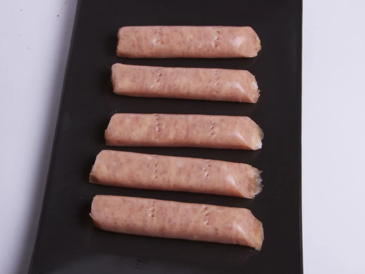 a black tray topped with five long  dogs
