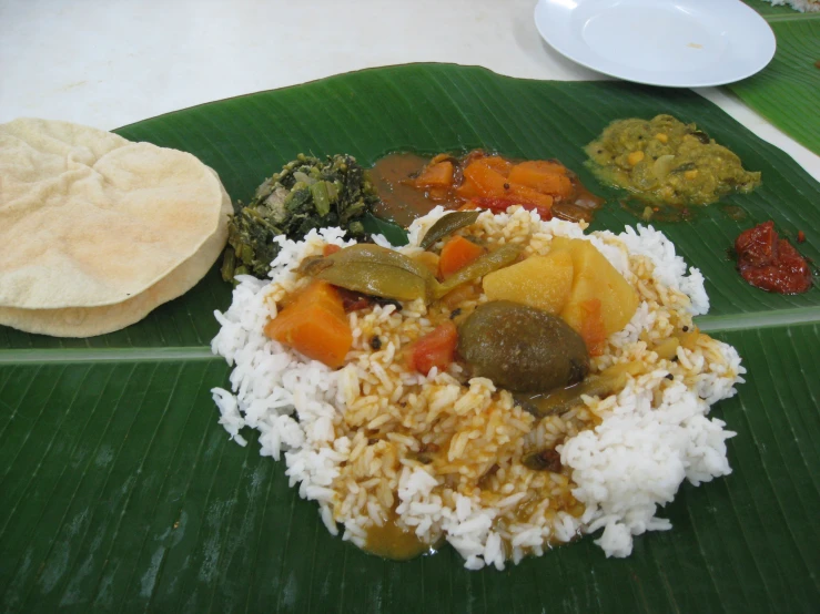 a banana leaf holds several different foods on a table