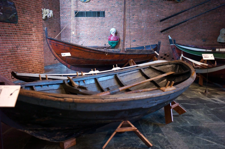 several boats are displayed in a museum of brick wall