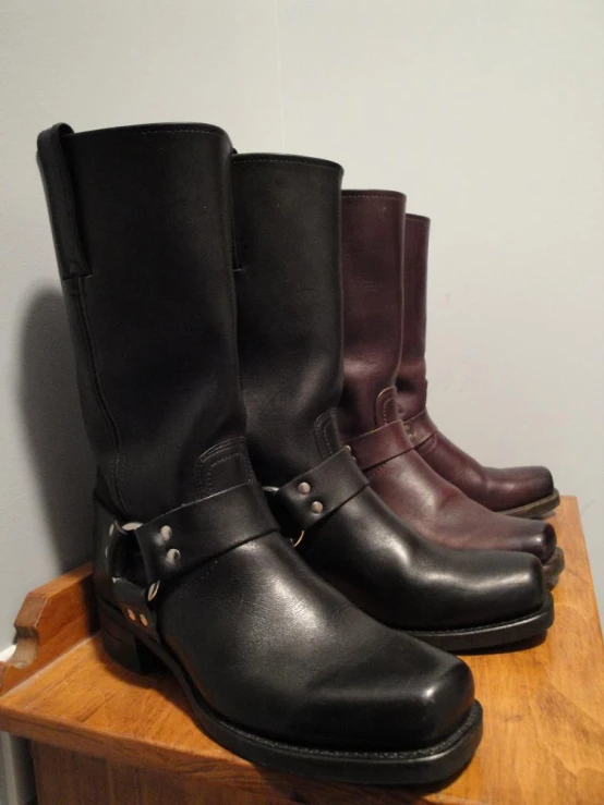 three pairs of black and brown boots sit on a shelf