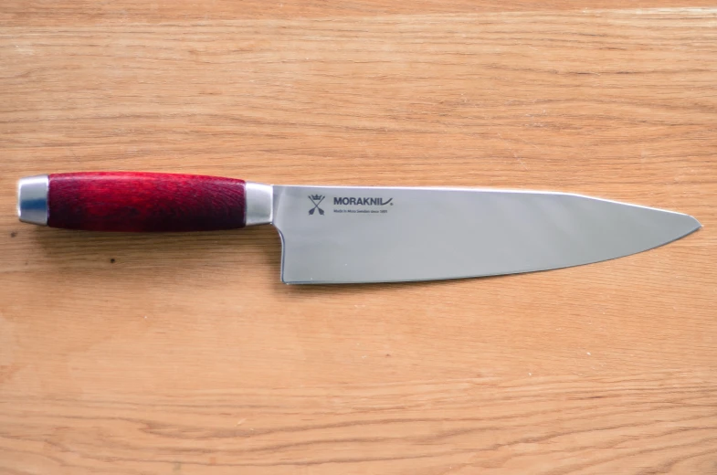 a red and silver knife sitting on top of a wooden table