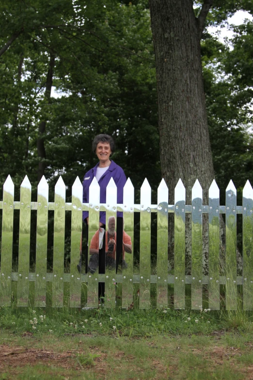 a woman with a blue shirt leaning against a white picket fence