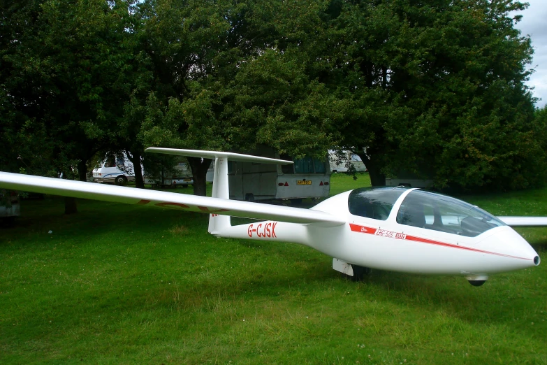 the small white plane is parked in the field