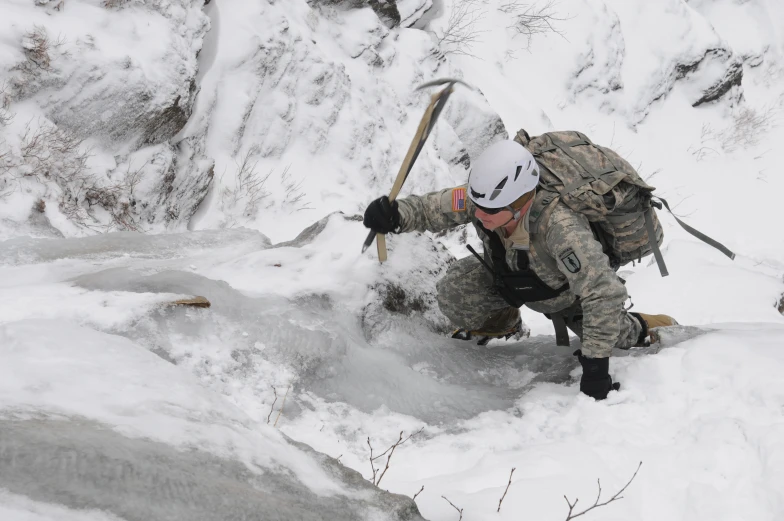 the person in military clothes is climbing a snow covered hill