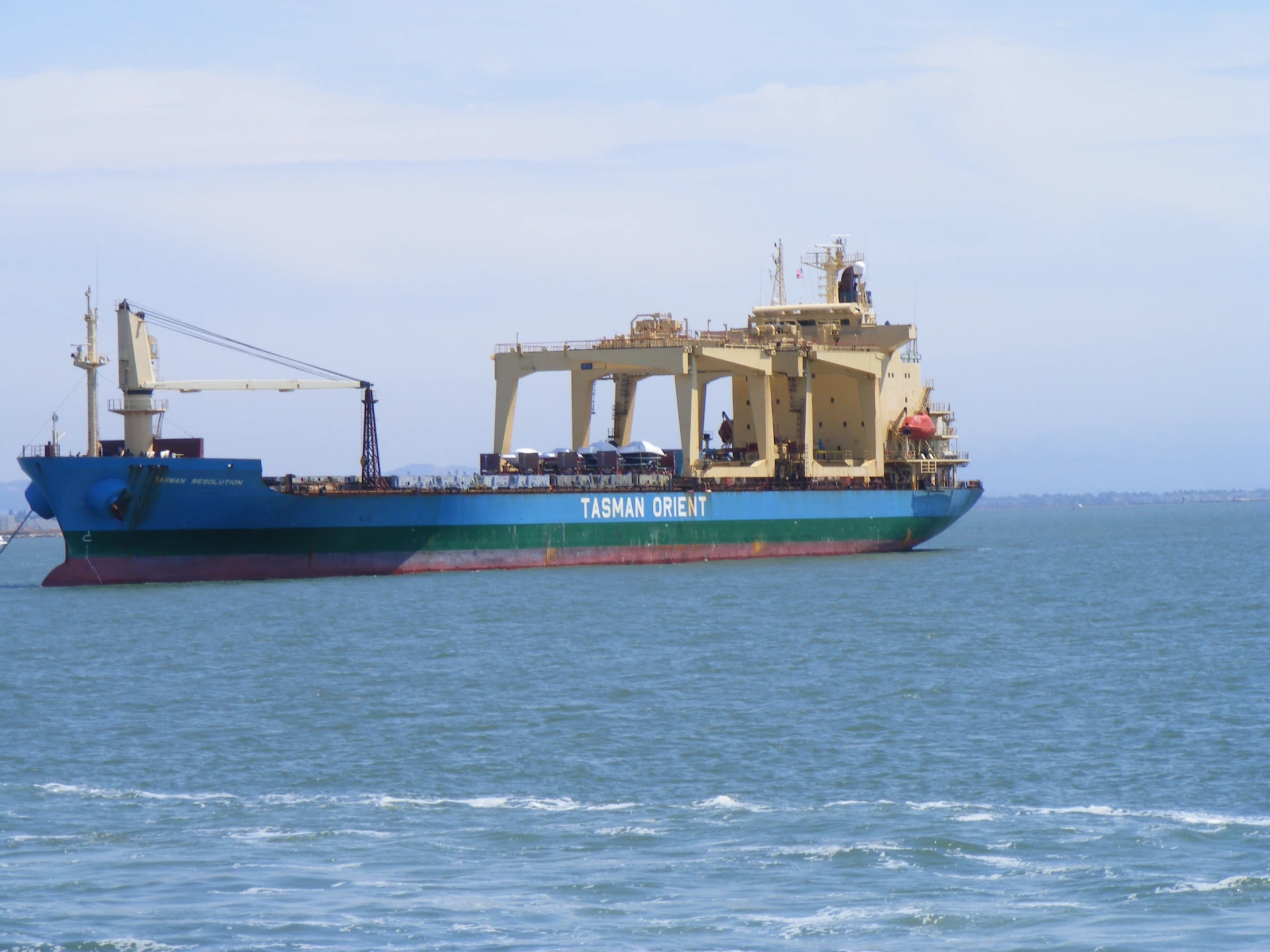 a blue and white cargo ship with people on top