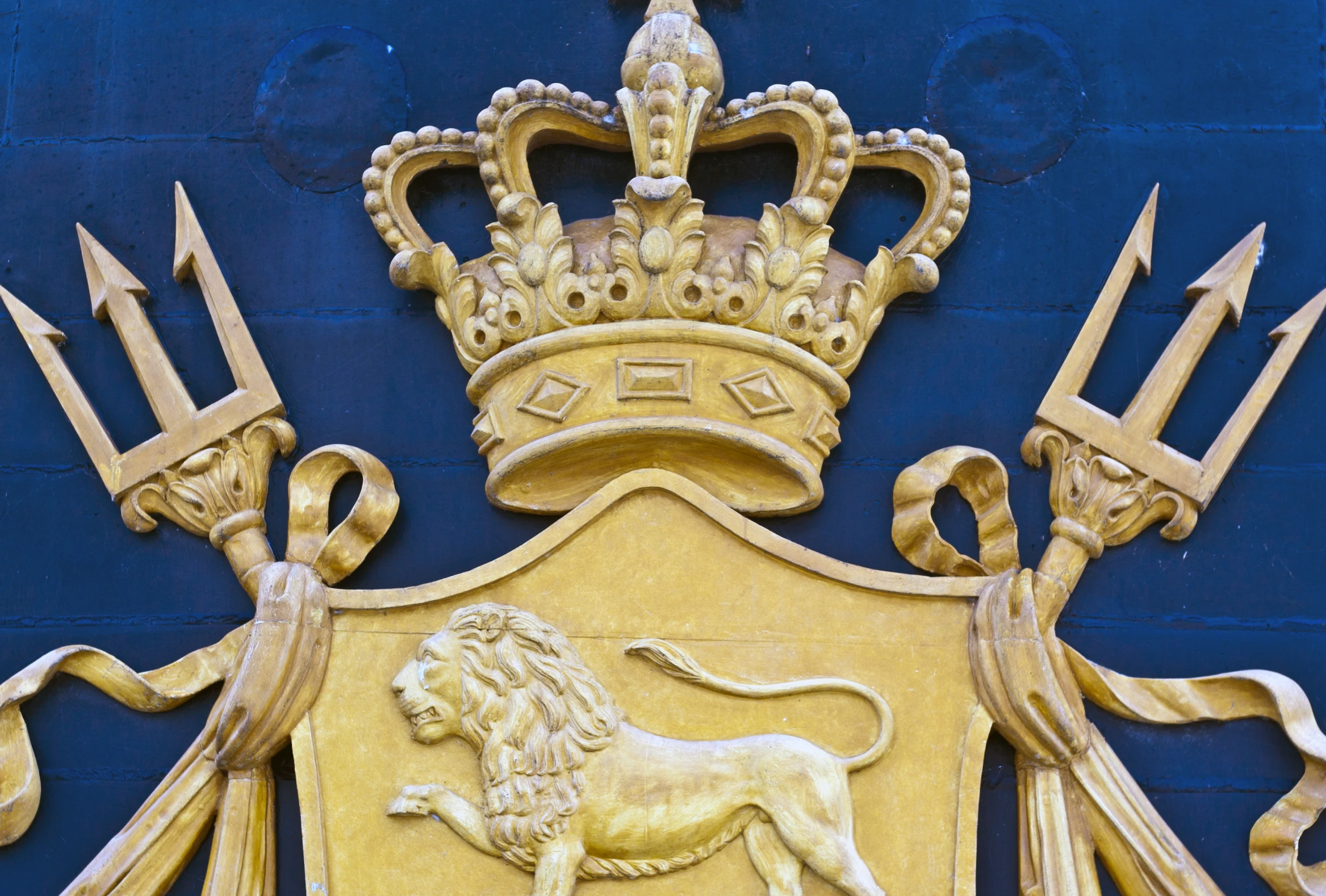 an ornately carved crown and coat of arms on a blue background