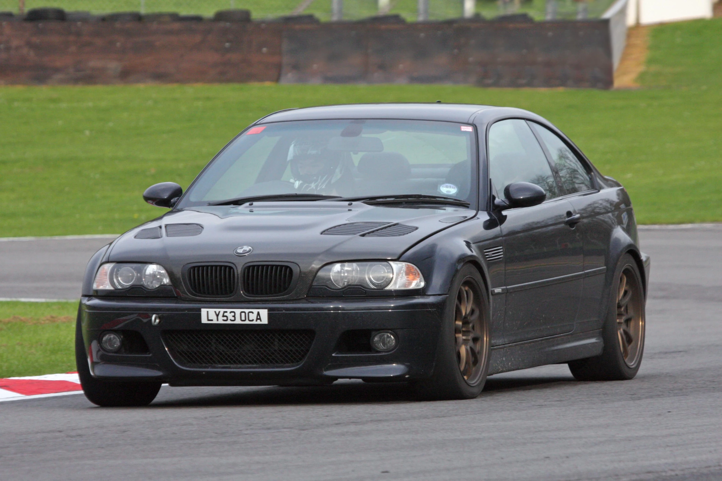 a black car driving around a track in the grass