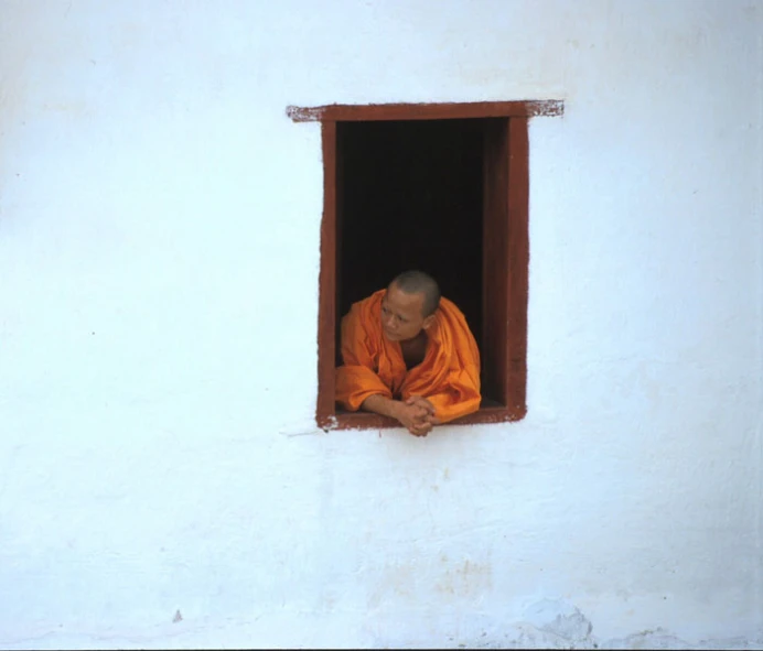 a monk sitting in an open window in a white wall