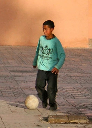 a boy in blue shirt playing with soccer ball