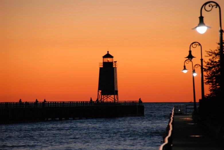 there is a light house near the water at sunrise