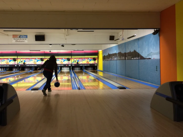 a woman walks in to the bowling lanes