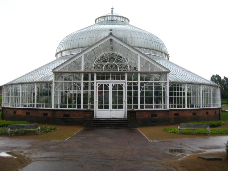 the white and clear greenhouse has steps leading to it