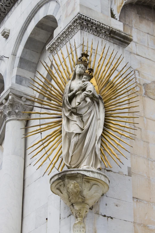 statue of an immaculate queen surrounded by a halo, in front of an ornate building