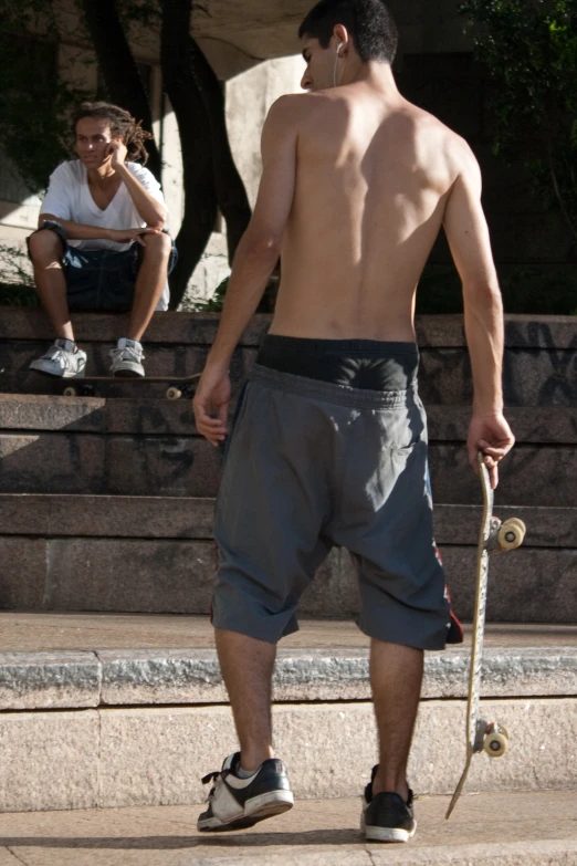 a man wearing shorts holds a skateboard