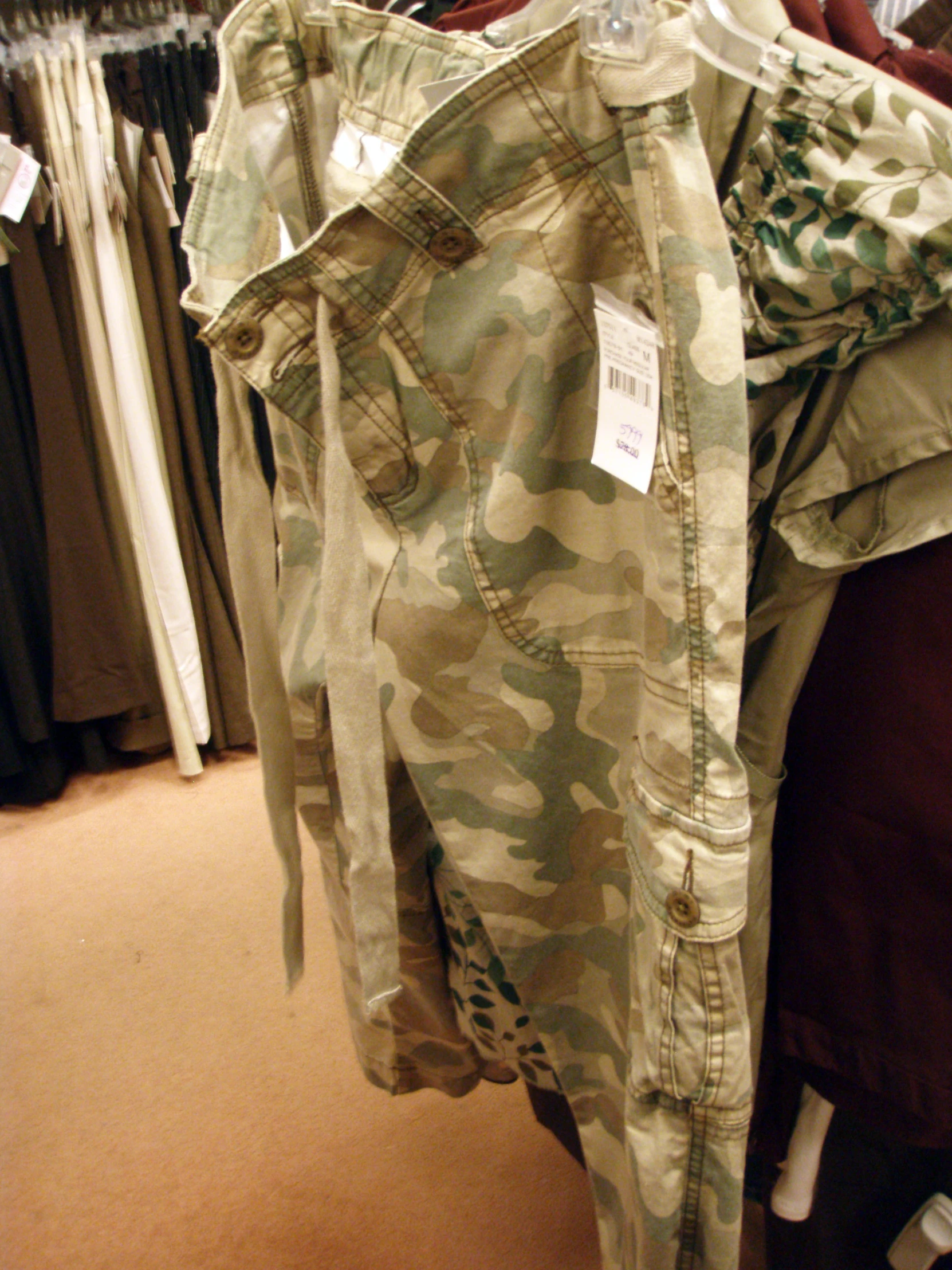 a white label on military fatigue pants hanging from clothes racks