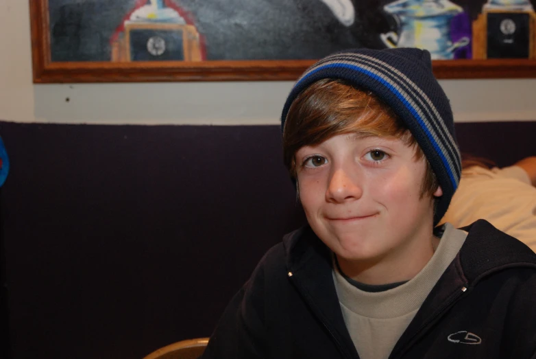 a young man is smiling and wearing a striped beanie