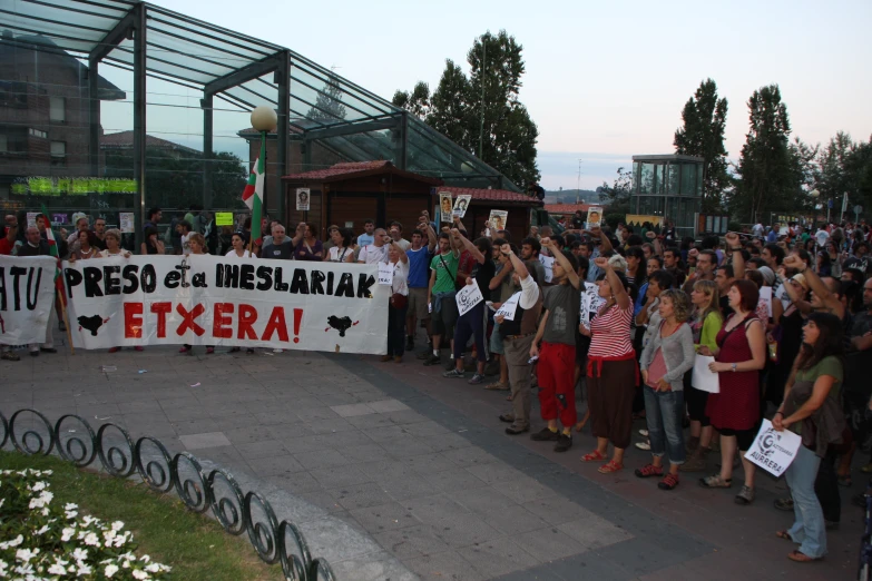 a large crowd is standing on the side of the street