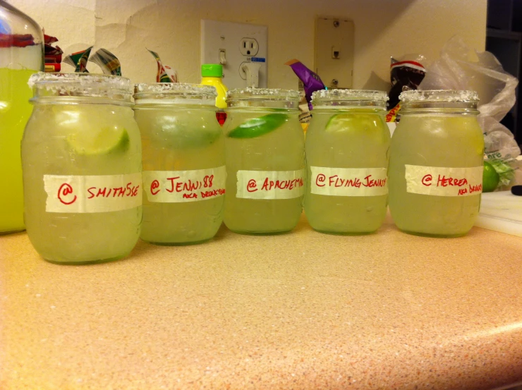 four different green drinks in glass containers on a counter