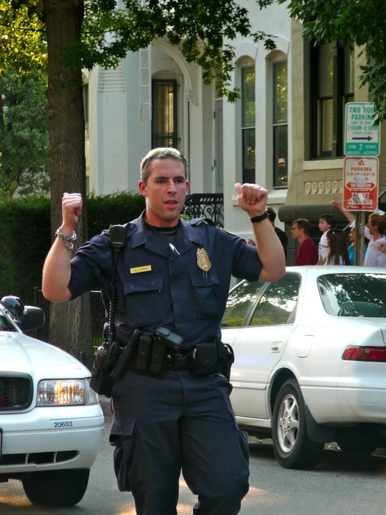 a cop points at soing while walking past some parked police cars