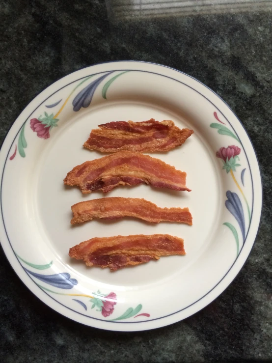 four pieces of bacon on a floral plate