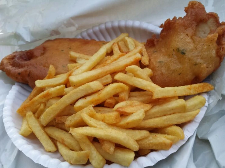 a paper plate filled with fried fish and fries