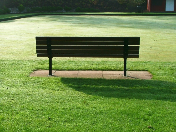 a park bench sits in a green field