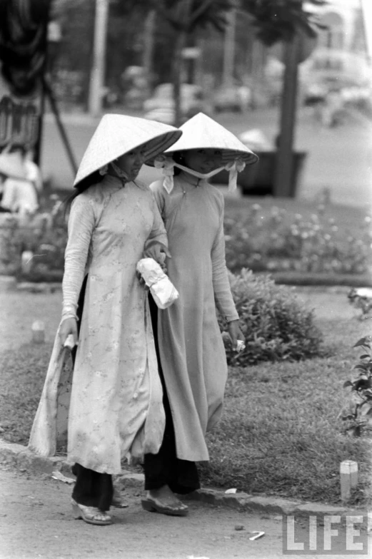 two girls carrying hats while walking down a street