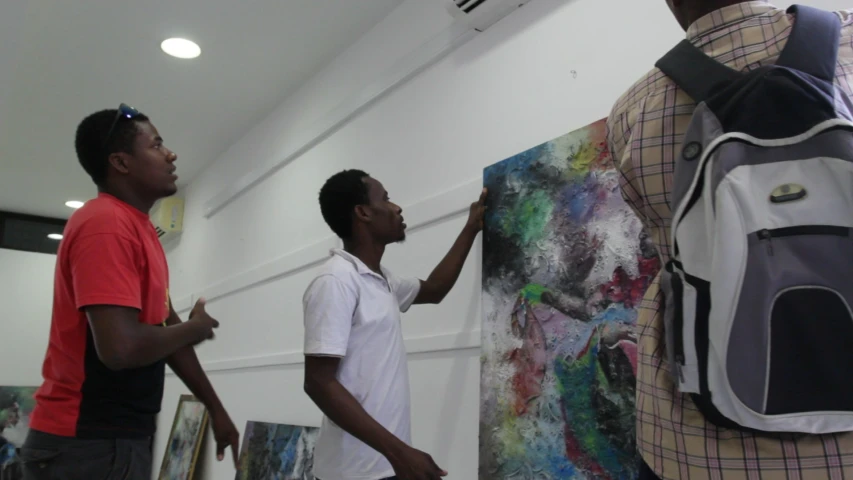 two men are painting large pictures in the middle of a room