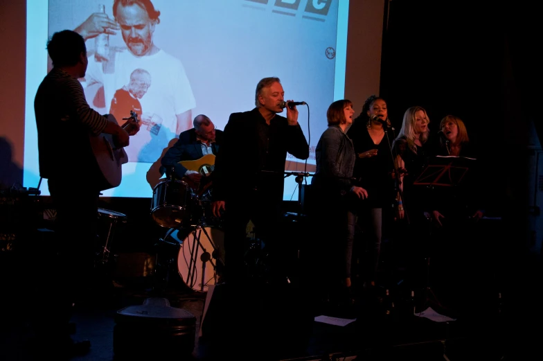 a group of people are standing in front of a projector screen