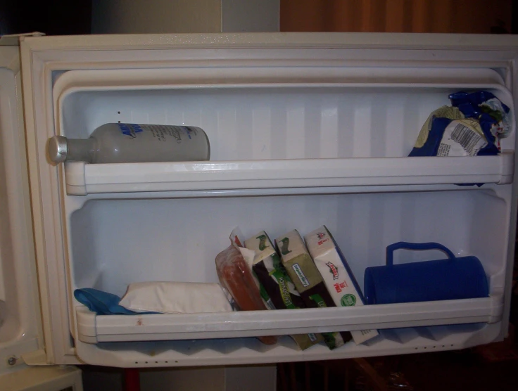 a refrigerator with milk, baby clothes and toys in it