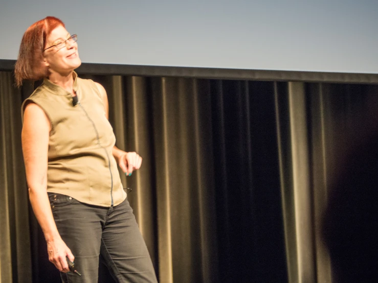 a woman in a tan shirt and black pants with an open mouth