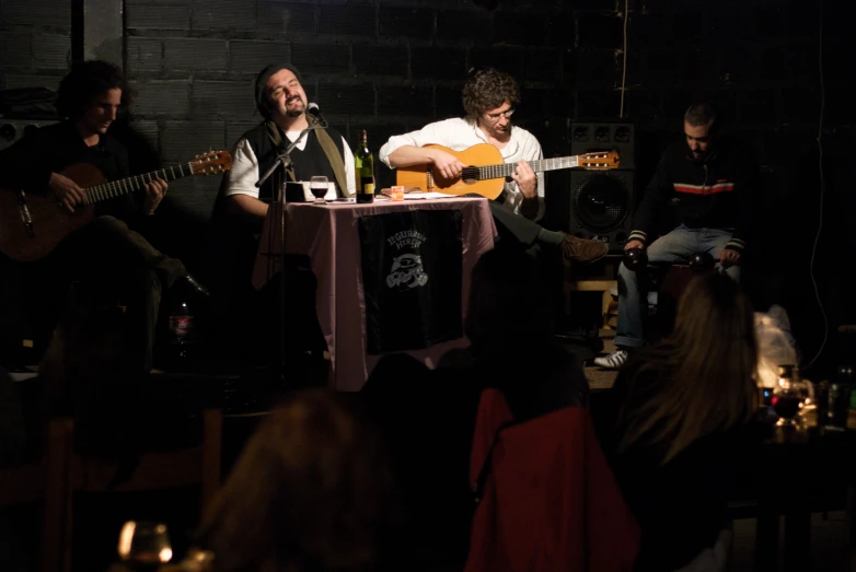 several men sitting at tables with guitars and microphones