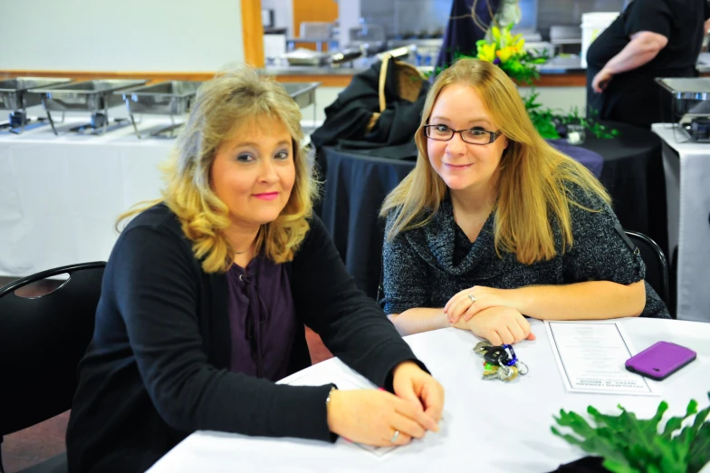 two women sitting at a table at an event