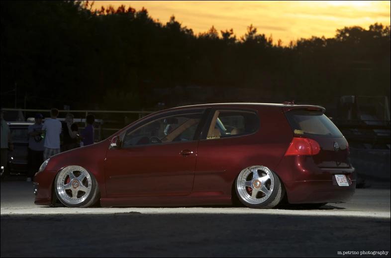 a red minivan parked in a parking lot with another car parked behind it