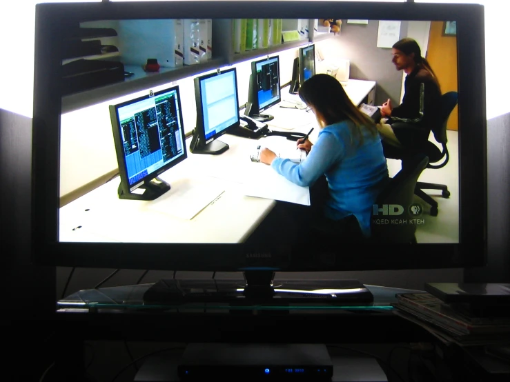 a woman working on some computer screens at her desk