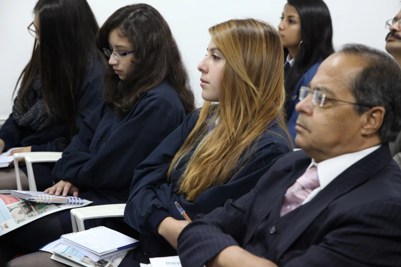 four people sit in rows on their knees as they read and talk