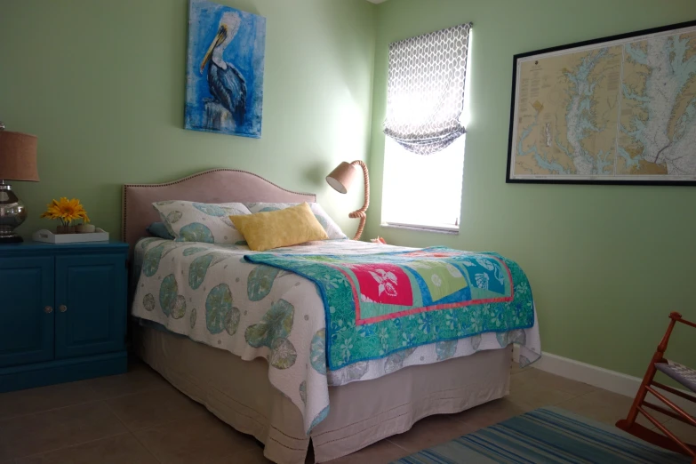 a large bed with floral bedspread next to a dresser and window